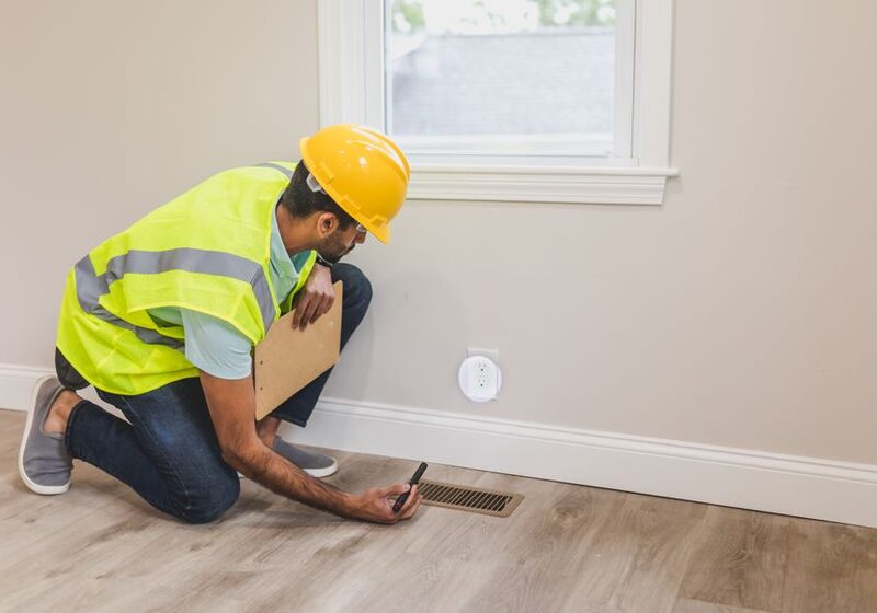 Technician inspecting a floor air vent for indoor air quality