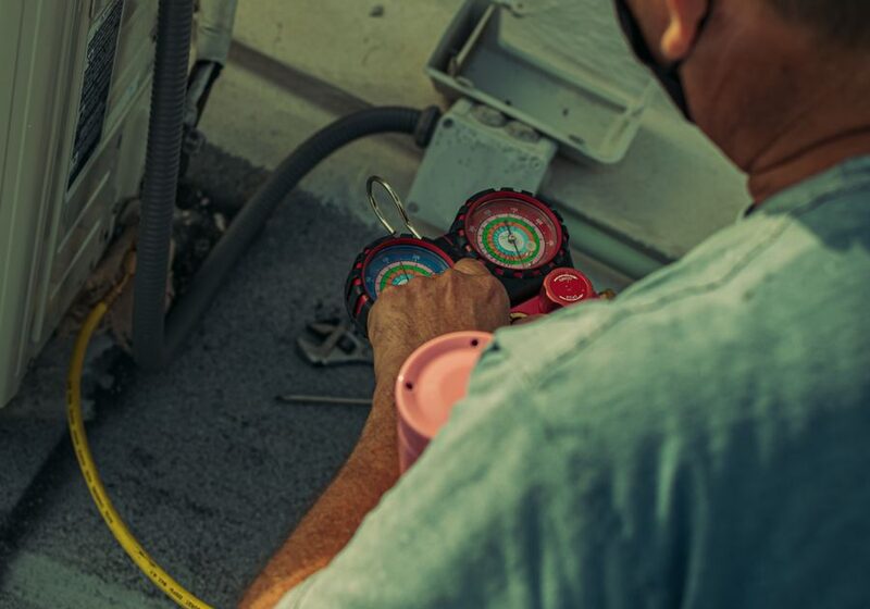 HVAC technician performing a maintenance tune-up with refrigerant gauges